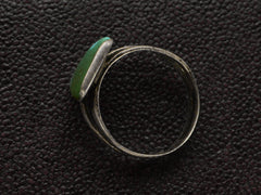 thumbnail of Side profile view of a sterling silver ring featuring a large, polished green triangular turquoise stone with natural matrix lines, set against a dark textured background.