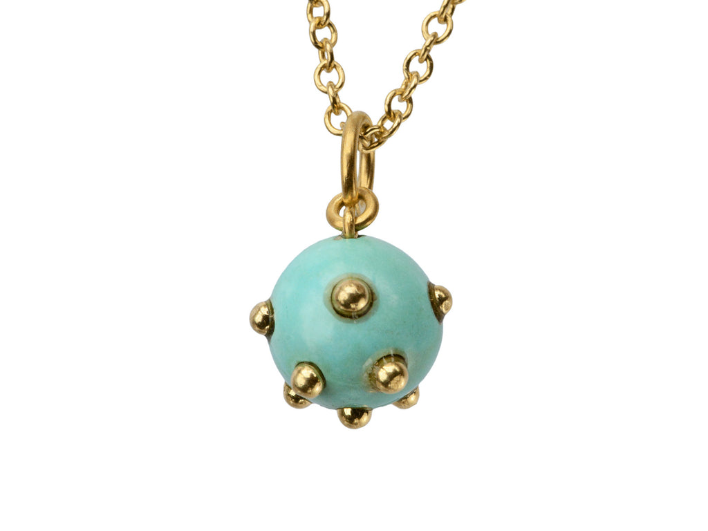 Vintage turquoise pendant studded with gold beads, hanging on chain against white background.