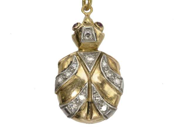 Vintage turtle shaped pendant in white and yellow gold with diamond and ruby details. shown on white background.