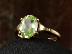 thumbnail of Angled front view of Art Deco ring with oval pale green stone set in rosy-yellow gold, shown on dark background.