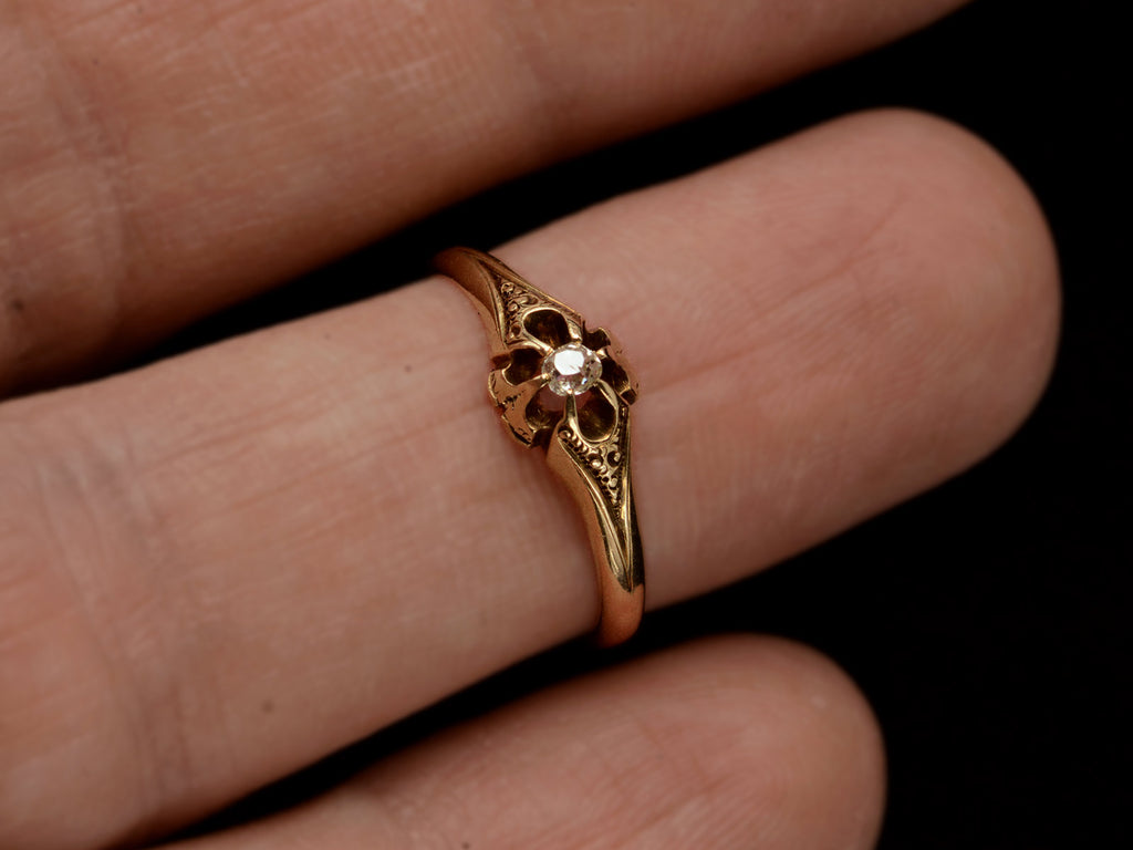 c1880 Victorian belcher setting engagement ring with a small old mine cut diamond set in yellow gold, shown on finger.