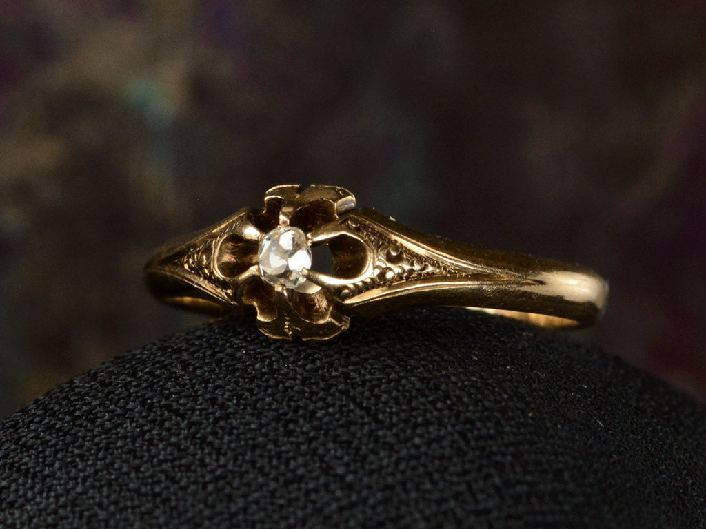 Angled right view of c1880 Victorian belcher setting engagement ring with a small old mine cut diamond set in yellow gold, shown on dark background.