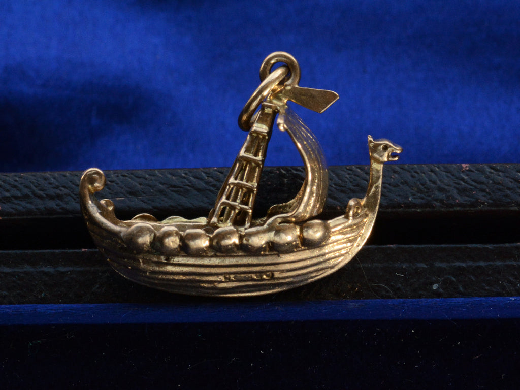 A yellow gold c1960 Viking Ship Charm, shown on dark blue background