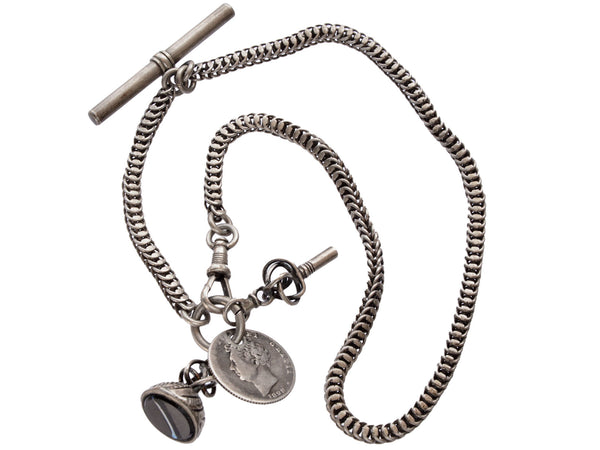 Detail of c1880 Victorian silver watch chain with black agate seal fob, a coin, and a watch key, shown on white background.