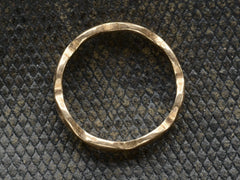 thumbnail of Side profile of a gold ring with a wave-form design, on a dark background.