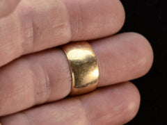 thumbnail of A wide patinated antique rosy-yellow gold wedding band, on finger.