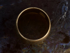 thumbnail of Side profile of a wide patinated antique rosy-yellow gold wedding band, on dark background.