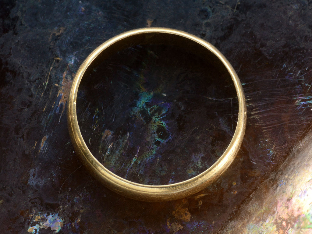 Side profile of c1920 Wide 18K yellow gold wedding band with edge detailing on dark background.