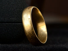 thumbnail of Detail of pitting on one side of antique 18K yellow gold wedding band, shown on dark background.