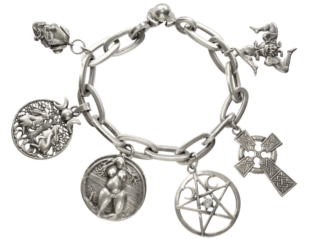 A vintage sterling silver charm bracelet with charms depicting mating frogs, a pair of rabbits perched beneath a tree under crescent moons, a nude woman, a pentagram, a Celtic cross, and the Sicilian Trinacria. On white background.