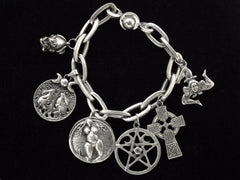 thumbnail of A vintage sterling silver charm bracelet with charms depicting mating frogs, a pair of rabbits perched beneath a tree under crescent moons, a nude woman, a pentagram, a Celtic cross, and the Sicilian Trinacria. On black background.