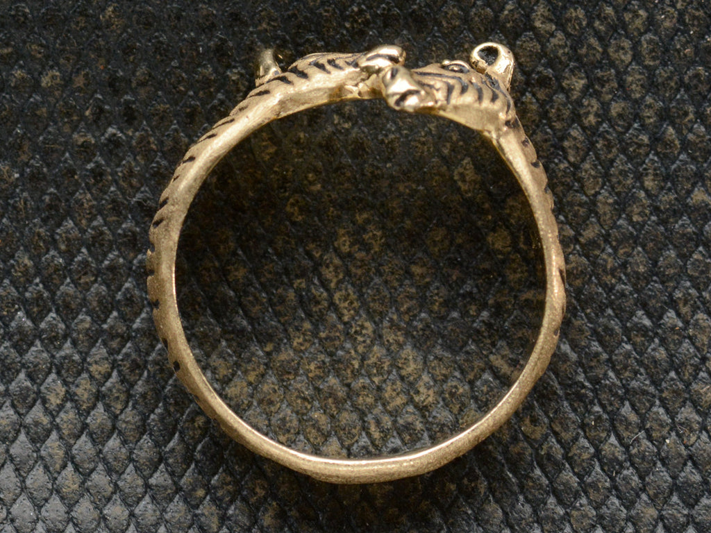 Side profile of a two-headed zebra ring in 14K with black details, shown on dark background.