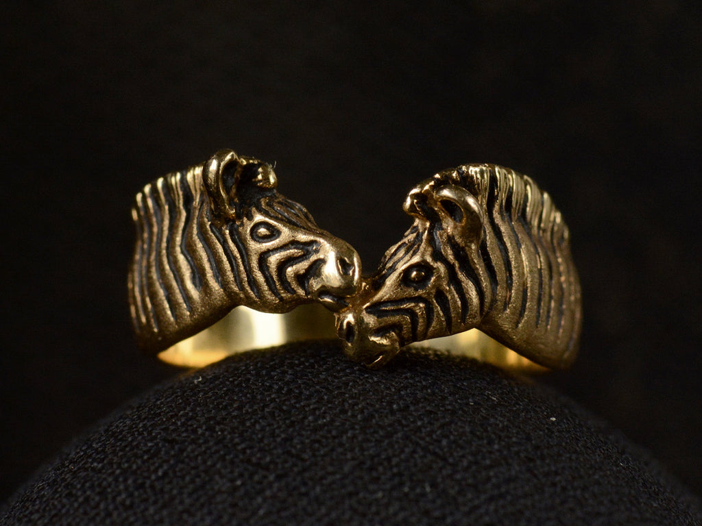 Front view of two-headed zebra ring in 14K with black details, shown on dark background.
