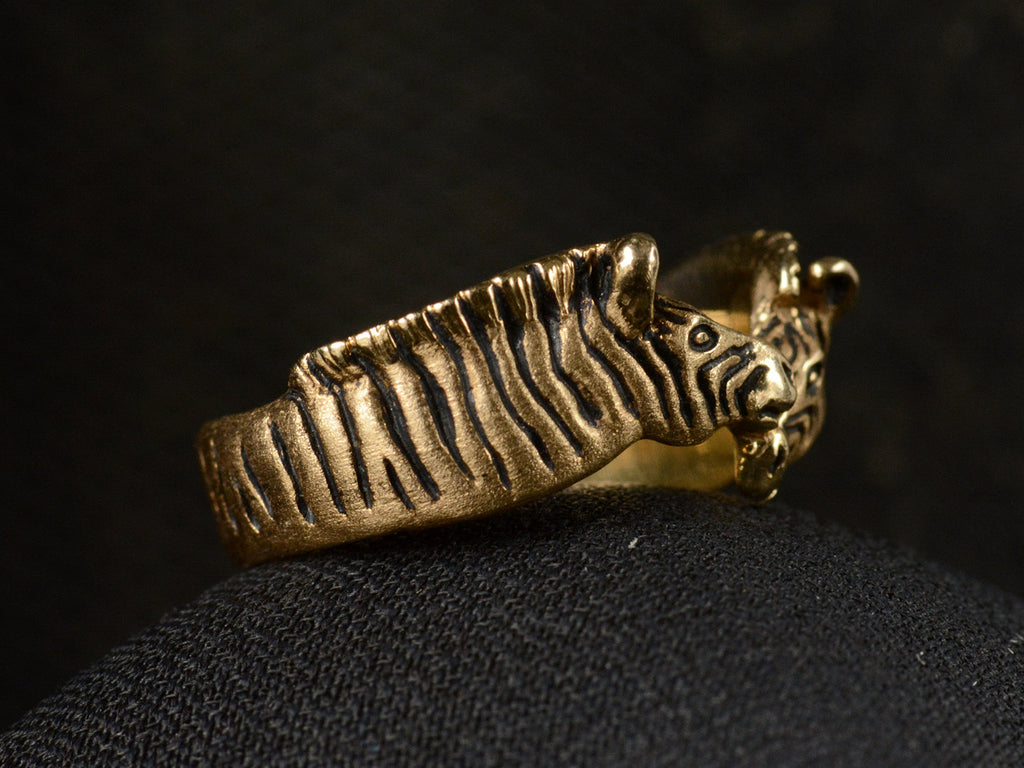 Left side view of two-headed zebra ring in 14K with black details, shown on dark background.