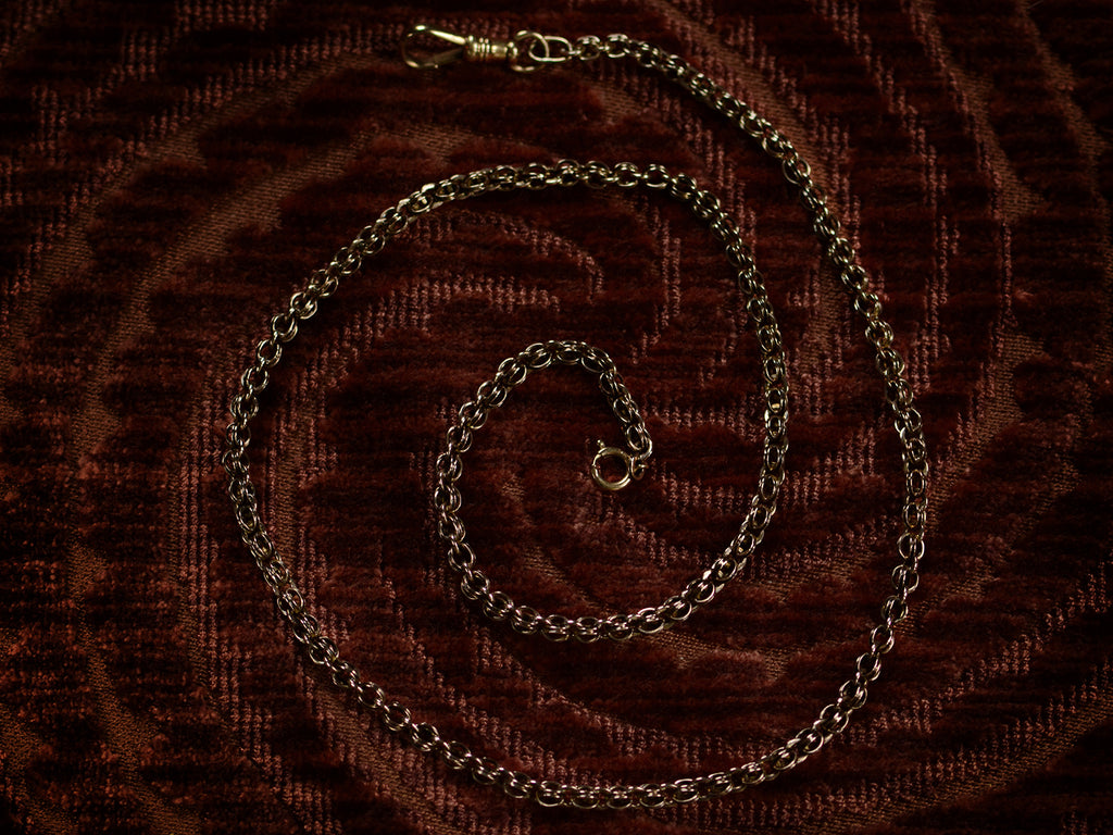 A sturdy Victorian-era gold chain with an unusual link, and a dog clip for attaching a pendant, in addition to a ring clasp that was likely added later. In 14K rosy-yellow gold with a blackened patina. Dates to c1880. Measures 19.5 inches.